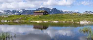 Stavatn Gölü'ndeki turba çatılı kulübeye dağlar yansıdı, Norveç