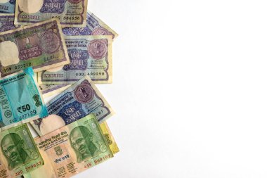 Çeşitli değerlerde klasik ve modern Hint banknotlarının karışımı, beyaz bir yüzeye yayılmış, eşsiz tasarımlarını ve para biriminin evrimindeki tarihsel önemini gösteriyor..