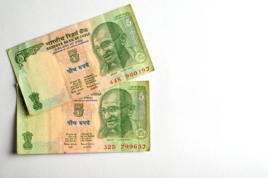 Basit bir ışık yüzeyinde karmaşık tasarımlar ve kültürel öneme sahip iki Hintli beş rupi bir araya getirilmiş..