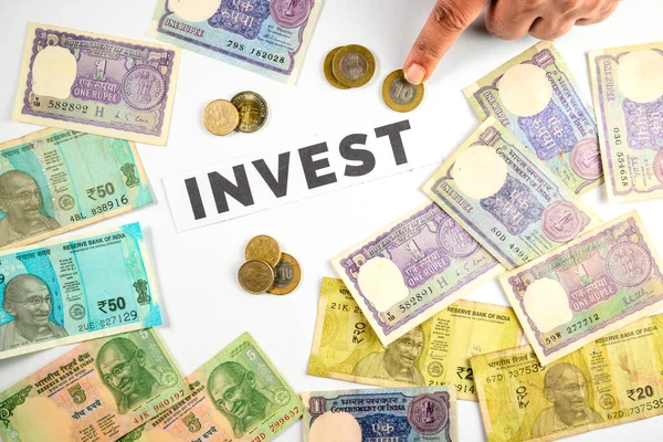 'Yatırım' kelimesi etrafında düzenlenmiş Hint Rupileri ve banknotları, mali planlama, tasarruf ve yatırım olanaklarını simgeliyor.