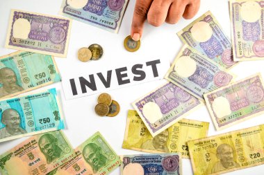 'Yatırım' kelimesi etrafında düzenlenmiş Hint Rupileri ve banknotları, mali planlama, tasarruf ve yatırım olanaklarını simgeliyor.