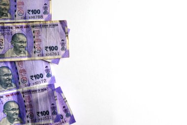 Temiz beyaz bir zemin üzerine sergilenen çoklu Hint 100 rupi banknotları ekonomi, zenginlik ve finansal kavramları sembolize ediyor. Hindistan 'da para, tasarruf veya ticari işlemler içeren temalar için harika.