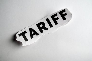 Kağıda basılmış, vurgu için yırtılmış 'Tariff' kelimesinin yakın plan görüntüsü.