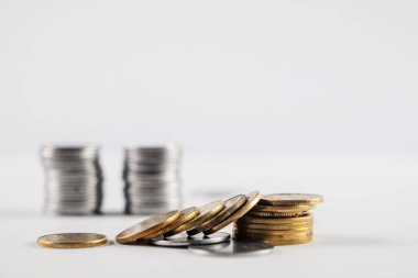 Servet, tasarruf ve finansal büyüme kavramlarını temsil eden beyaz bir yüzeye yerleştirilmiş gümüş ve altın sikke yığınları. Mali başarıyı, yatırımları ve parasal temaları göstermek için mükemmel.