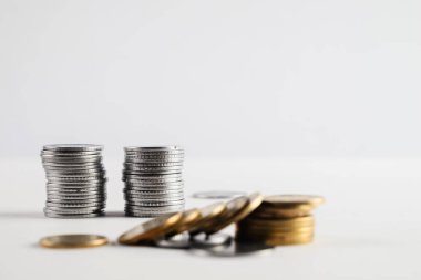 Servet, tasarruf ve finansal büyüme kavramlarını temsil eden beyaz bir yüzeye yerleştirilmiş gümüş ve altın sikke yığınları. Mali başarıyı, yatırımları ve parasal temaları göstermek için mükemmel.