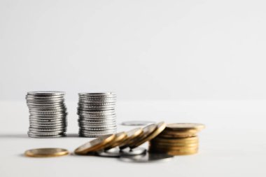 Servet, tasarruf ve finansal büyüme kavramlarını temsil eden beyaz bir yüzeye yerleştirilmiş gümüş ve altın sikke yığınları. Mali başarıyı, yatırımları ve parasal temaları göstermek için mükemmel.