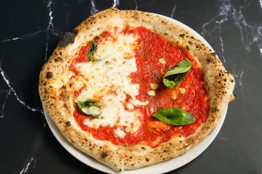 Margherita ve marinara stillerinin birleşiminden oluşan yarı yarıya pizza manzarası. Bir tarafı erimiş mozzarella ve fesleğenle kaplıyken, diğer tarafı domates sosu, sarımsak dilimleri ve bitkilerle kaplı.