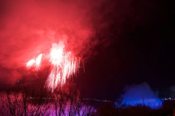 Niagara falls, ontario, canada - 20. Mai 2018: niagara falls beleuchtet in der Nacht von bunten Lichtern mit Feuerwerk — Stockfoto