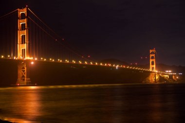 San Francisco, California, Amerika Birleşik Devletleri - 25 Kasım 2018: Fort Point'ten görülen Golden Gate Köprüsü, arkasında gökyüzünde yıldız izleri ile gece parlıyor