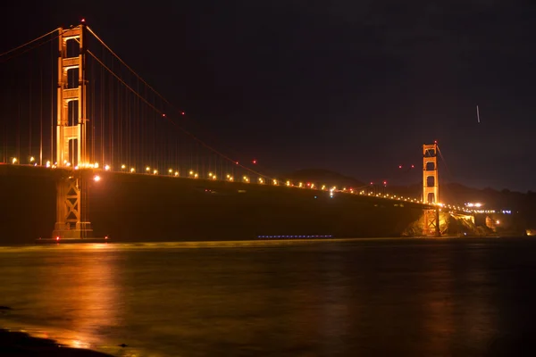 SAN FRANCISCO, CALIFORNIA, ESTADOS UNIDOS - 25 DE NOV DE 2018: El puente Golden Gate visto desde el mirador de Fort Point brilla en la noche con senderos de estrellas en el cielo detrás de él —  Fotos de Stock