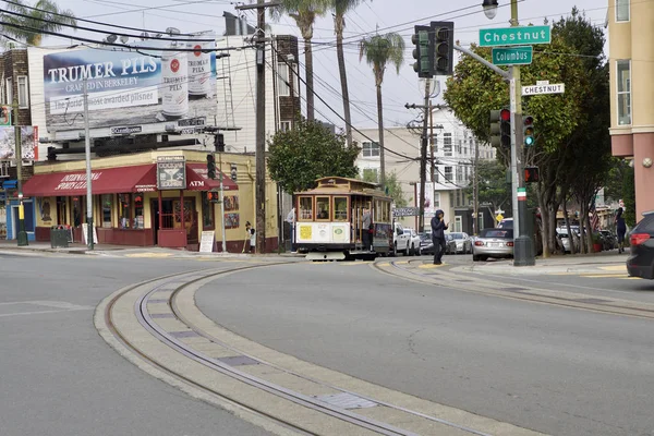 SAN FRANCISCO, CALIFORNIA, ESTADOS UNIDOS - NOV 25, 2018: Os passageiros desfrutam de um passeio em um teleférico e cruzam a rua Columbus e Chestnut. É o mais antigo transporte público mecânico que está em — Fotografia de Stock