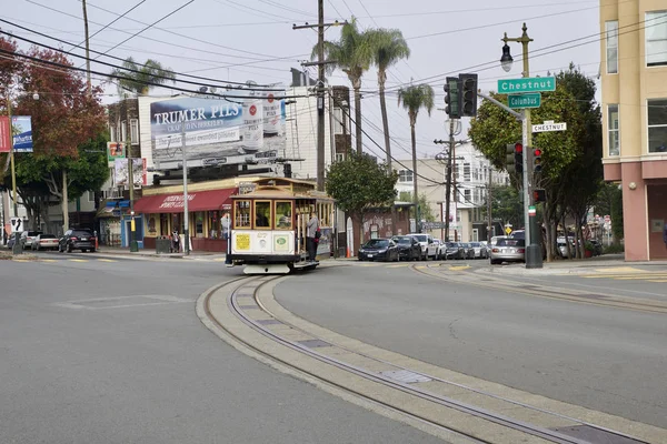 SAN FRANCISCO, CALIFORNIA, ESTADOS UNIDOS - NOV 25, 2018: Os passageiros desfrutam de um passeio em um teleférico e cruzam a rua Columbus e Chestnut. É o mais antigo transporte público mecânico que está em — Fotografia de Stock