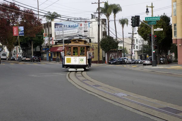 SAN FRANCISCO, CALIFORNIA, ESTADOS UNIDOS - NOV 25, 2018: Os passageiros desfrutam de um passeio em um teleférico e cruzam a rua Columbus e Chestnut. É o mais antigo transporte público mecânico que está em — Fotografia de Stock