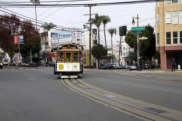 SAN FRANCISCO, CALIFORNIA, ESTADOS UNIDOS - NOV 25, 2018: Os passageiros desfrutam de um passeio em um teleférico e cruzam a rua Columbus e Chestnut. É o mais antigo transporte público mecânico que está em — Fotografia de Stock