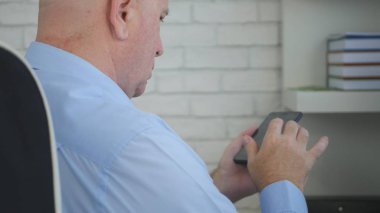 Yöneticisi sandalye Smartphone kullanarak metin içinde oturan işadamı