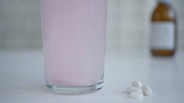 Tıp efervesan hap pembe bir bardak su kabarcıkları ile çözünmüş