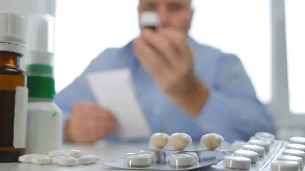 Man With Pills in Hand and a Medical Recipe