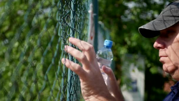 Mann Hinter Metallzaun Blickt Enttäuscht Nach Vorn — Stockvideo