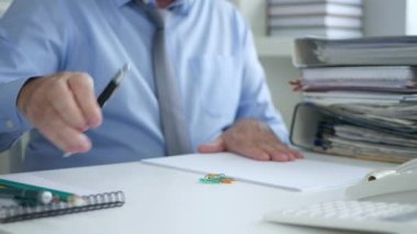 İşadamı Office Oda yazılı olarak bir kalem kullanarak muhasebe belgeleri
