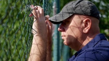 Hayal kırıklığına uğramış adam metalik bir çit üzülmüş