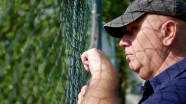 Bir şişe su el ile metalik bir çit arkasında umutsuz kişi