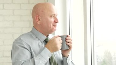 İşadamı Office pencerenin önünde içinde gülümseme ve bir fincan çay içmek