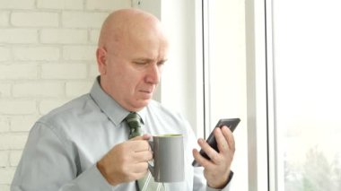 İşadamı kullanma Smartphone Online ve bir fincan sıcak çay veya kahve keyfini çıkarın