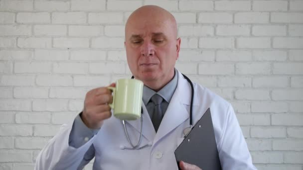 Imagen del médico Disfrute de una taza de café o té con un portapapeles en la mano — Vídeos de Stock