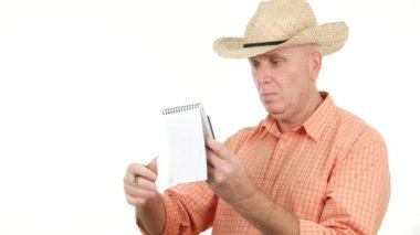 Ciddi ve meşgul çiftçi okumak ve küçük bir cüzdan kullanarak notlar almak