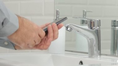 Adamı durdurmak okuma mesajları cep telefonu ve banyo elinde yıkama başlangıç