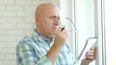 İşadamı gözlük takan bir kalem ve bir cüzdan kullanarak notlar almak