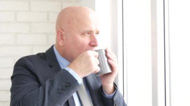 İşadamı derin derin düşünür ve etkinlik rahatlatıcı ofisinde sıcak bir içkinin tadını çıkarın