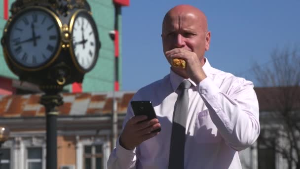 Επιχειρηματίας Τρώγοντας Ένα Σνακ Και Διαβάσετε Μηνύματα Online Cellphone Δρόμου — Αρχείο Βίντεο
