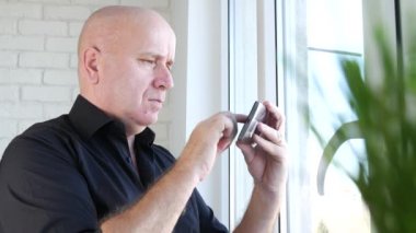 Oda ofis içinde işte üzgün işadamı üstünde belgili tanımlık pencere kalmak ve bir hücre telefon bekleyin