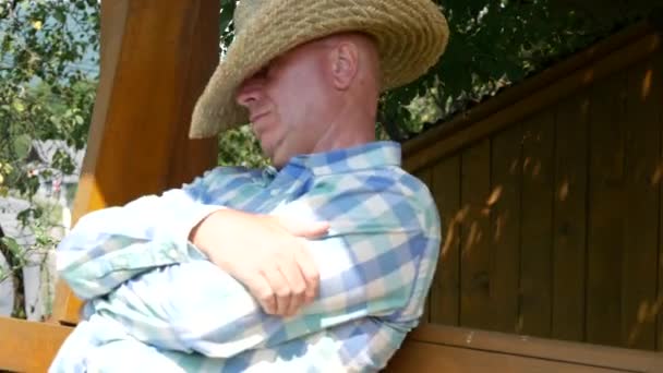 疲れて農民睡眠と彼の目を覆う帽子の外ロッカーでスイング — ストック動画