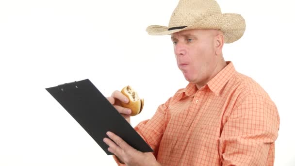 Utsvultna bonden tar en paus på jobbet äter en god smörgås och läsa från Urklipp — Stockvideo