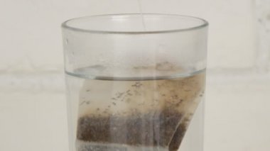 Adam bir bardak sıcak su ve çay poşeti ile görüntüsüyle sıcak içecek hazırlama kapatın