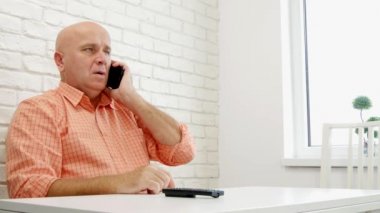 Meşgul adam görüntü kullanarak Tv Uzaktan ve aynı zamanda cep telefonunuza konuşuyor