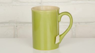 Yeşil bir fincan çay poşeti ile sabah sıcak ve tatlı çay yapma