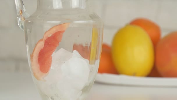 Hombre en la cocina Preparando una limonada fresca con limón helado y rodajas de naranja — Vídeos de Stock