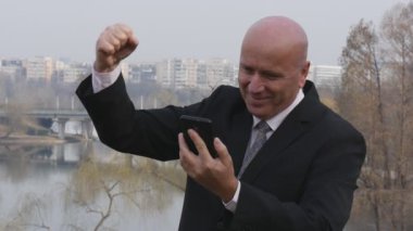 Ağır çekim mutlu işadamı oku cep iyi haber ve yapmak kazanan jestleri