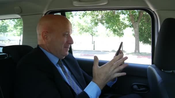 幸せな携帯を身振りで示す後部座席では、タクシーのビジネスマンは、グッド ニュースを読む (Uhd、ウルトラ Hd, Ultrahd 超高精細 4 k、3840 x 2160) — ストック動画