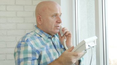 Bir sabit hat telefon bağlantı kullanarak konuşan işadamı