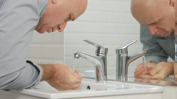 Hombre en el baño lavándose las manos y la cara con agua dulce en el fregadero — Foto de Stock