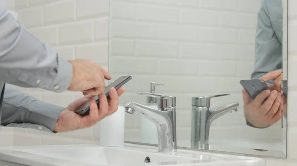 Empresario en Cuarto de Baño Uso Teléfono Móvil Accediendo a Mensajes Urgentes Online — Foto de Stock