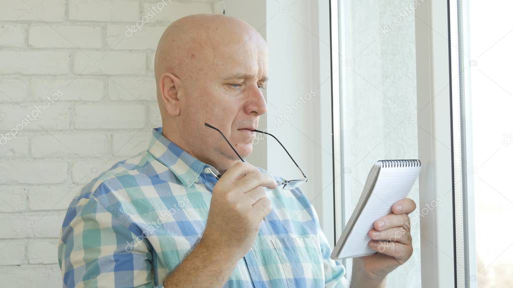 Businessman Wearing Eyeglasses Calculate and Take Notes Using a Pocketbook