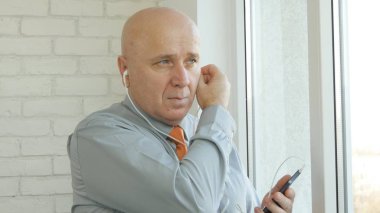 Smartphone ile kulaklık kullanarak iç ofis işadamı görüntüsü