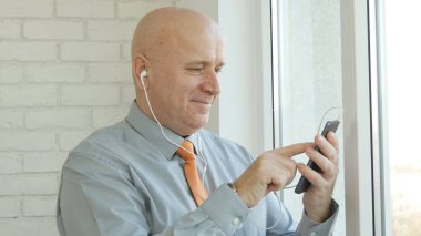 Smartphone ile kulaklık kullanarak iç ofis işadamı görüntüsü