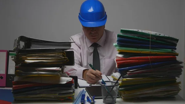 Ingeniero con casco firmar documentos técnicos en la sala de archivos —  Fotos de Stock