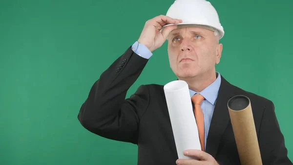 Ingénieur sérieux Gardez son casque avec la main et levez les yeux — Photo